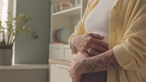 Femme enceinte caressant son ventre à la cuisine