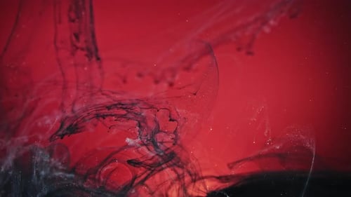 Ink Flowing in Water on Red Background