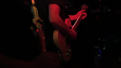 Guitar players on dark stage at a concert rocking the audience, close up shot of hands playing with