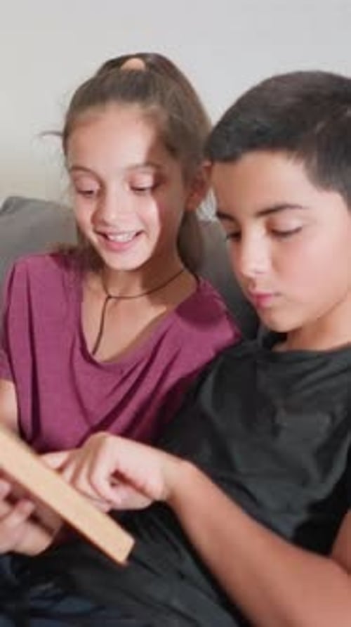 Friends Enjoy Interactive Reading Session Pointing at Book Together on Couch