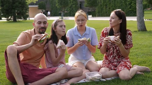 A Happy Family with Teenage Children Eating Sandwiches in the Park on the Grass