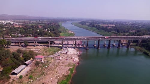 vehicles moving on Tilwara bridge with river and crop fields lands at day time, pan shot, drone shot