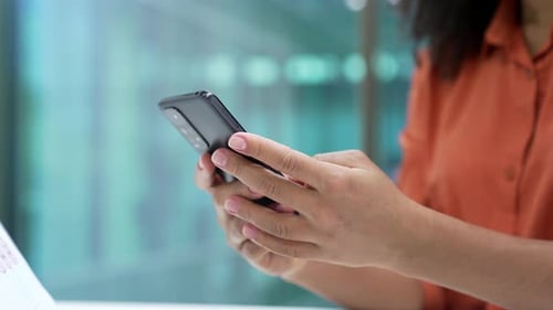 Close up of female hands holding using mobile phone in business office. African american