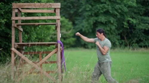 Man Practicing Martial Arts Kicks in a Field