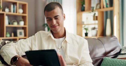 Smiling Young Adult Interacting with a Tablet at Home