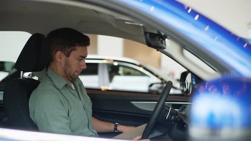 Side View of Happy Male Customer Sitting in Driver Seat in New Automobile Inside Modern Showroom