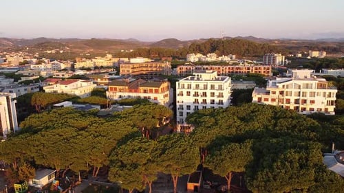 Aerial above Golem, Albanian coastal town with hotels and apartment buildings, hill landscape.