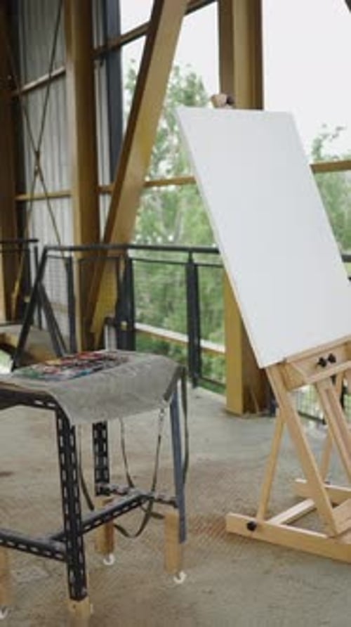 A Canvas Next to a Table Filled with Paintings in a Building
