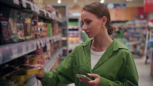 Woman Choosing Product Using Smartphone in Supermarket