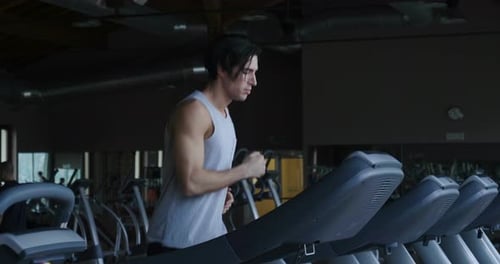 A guy in the gym to stay fit and have defined muscles or lose weight runs on the treadmill with a