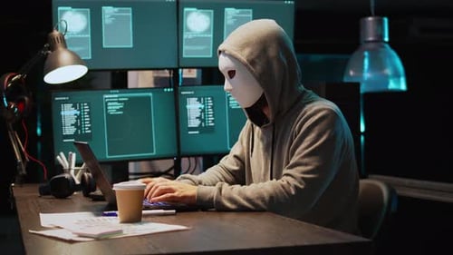 Un cyberescroc porte un masque et une capuche pour pirater un système informatique