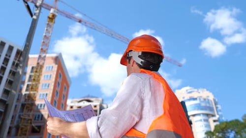 Construction Foreman Reviewing Blueprints on Sunny Day