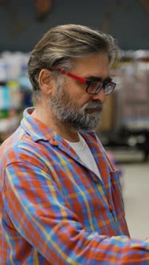 Senior Man Choosing Cleaning Spray in a Supermarket Aisle
