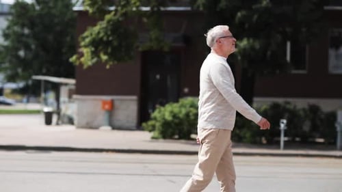 Senior man enjoying a summer walk down a sunny city street
