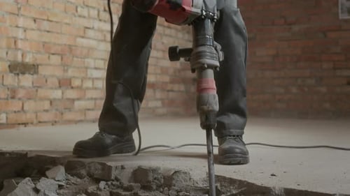 Construction Worker Demolishing Interior Concrete with Jackhammer