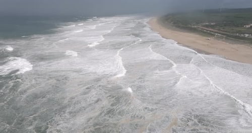 Aerial drone shot of Atlantic Ocean waves coming into shore on a stormy day with giant waves in