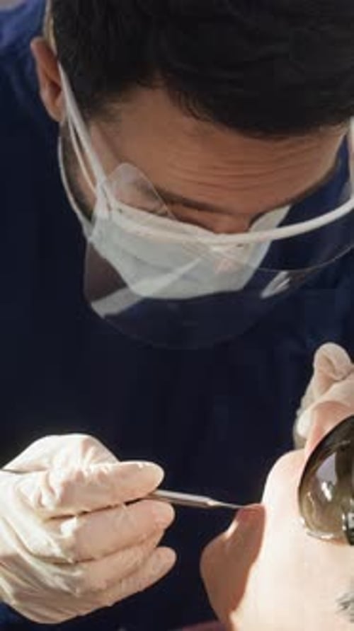 Dentist Examining Patient Teeth Under Overhead Light Close Up