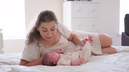 Woman Interacting With Infant Lying on Bed