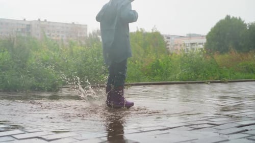 Child Revels in Joy of Jumping in Puddle