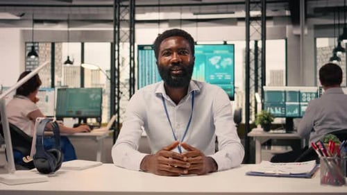 Smiling Man at Desk in Modern Office Talking