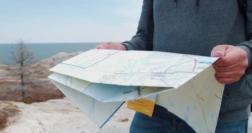 Person Holding Map near the Coastline