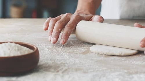 Person Rolling Dough on Floured Counter
