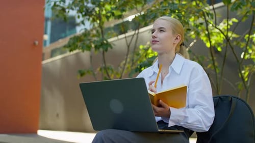 Woman Works on Laptop and Notebook Outdoors
