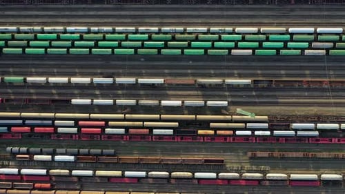 Flying above industrial railroad station with cargo trains and freight containers. Steady Drone shot