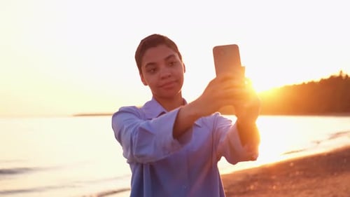 Young Woman Taking Photo at Beach Sunrise