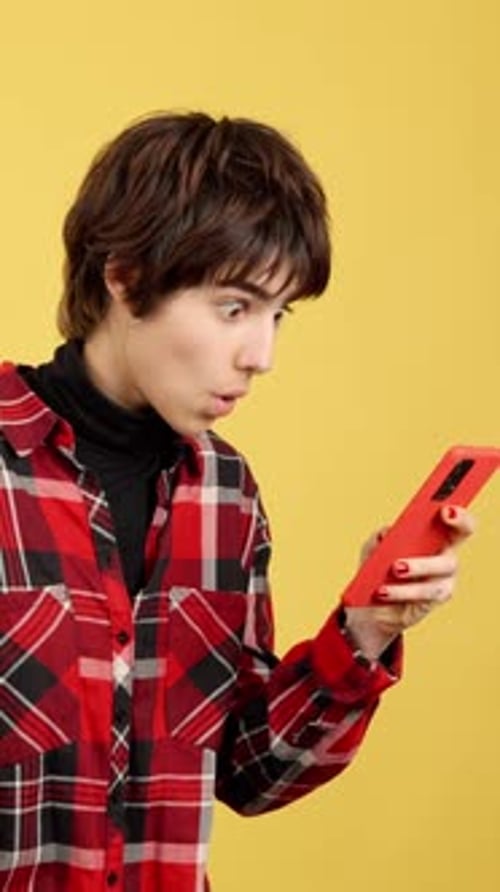 Young Adult Looks Surprised at Cell Phone Screen