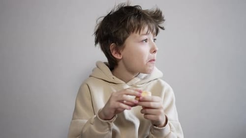 Calm brunet teenager eating a tangerine.