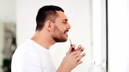 Man Combs His Beard in the Bathroom