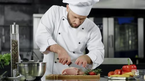 Chef cuts meat in a restaurant kitchen