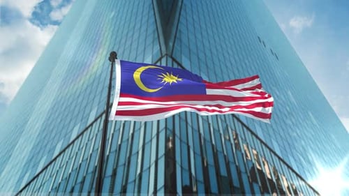 Waving Malaysian Flag in Front of Modern Skyscraper