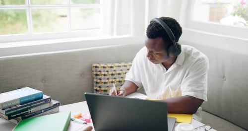 Writing, cafe and black man with headphones on laptop for online learning, studying and education