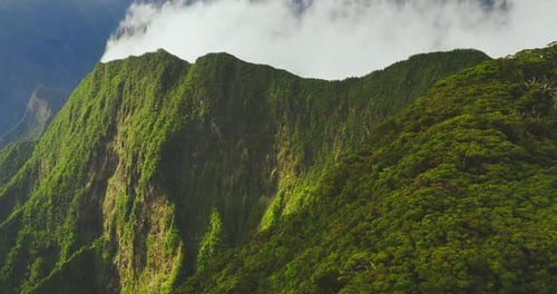 Nubes que se ciernen sobre empinadas y exuberantes montañas y valles tropicales