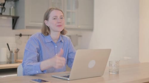 Smiling Woman Working on Laptop Gives Thumbs Up