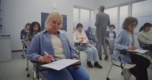 Adults Attending Class in Bright Room Taking Notes