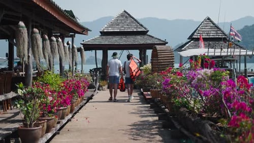 Two Men Walk to the Pier Near the Jetty Before Kayaking