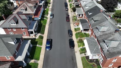 Straight street of american housing area. Row of houses with red bricks and porch at sunny day. Park