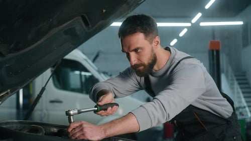 Car Mechanic Vehicle Service Worker Working in Workshop Garage Using Wrench Tool to Repair Engine
