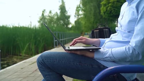A man works on a laptop outdoors