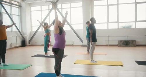 Coach with Group Prepares for Yoga Class in Fitness Gym