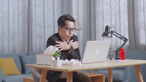 Sick Man Working at Home on Laptop