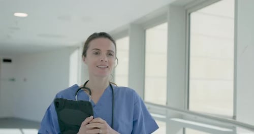 Female Nurse with Medical Tablet Walking in Hospital