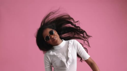 Happy Woman Dancing with Sunglasses on Pink Background