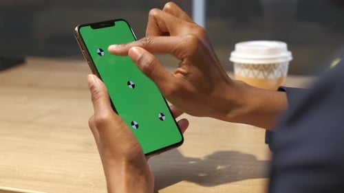 A black woman with a smartphone in her hand. Tap gestures on the touchscreen.