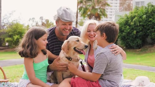 Family enjoying picnic with golden retriever dog