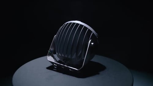 Runder LED-Projektor dreht sich auf einem Ständer im dunklen Studio