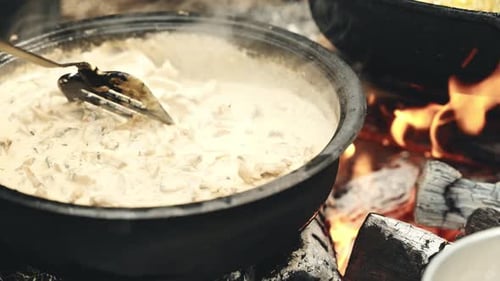 Cooking delicious stew on bonfire in wilderness, close up view